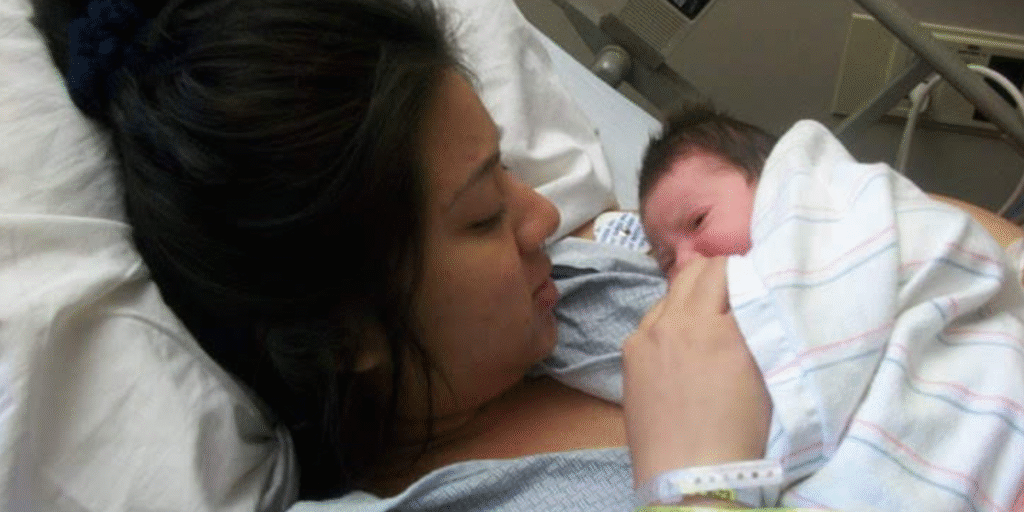 Madre migrante sosteniendo a su hija recién nacida en una sala de hospital, un momento de amor puro.