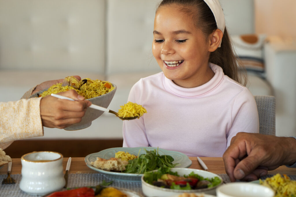 Niña feliz durante una comida saludable en familia.