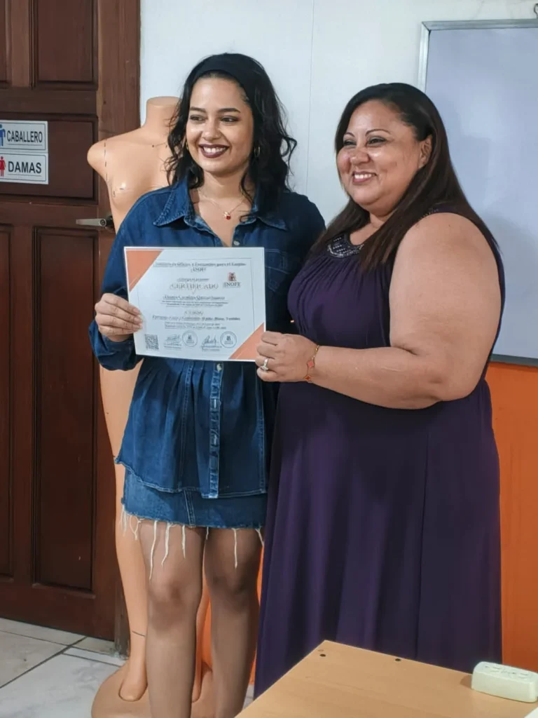 Alejandra Jiménez, mamá emprendedora y diseñadora en Nicaragua, entrega un certificado de reconocimiento a una estudiante durante una ceremonia de graduación.
